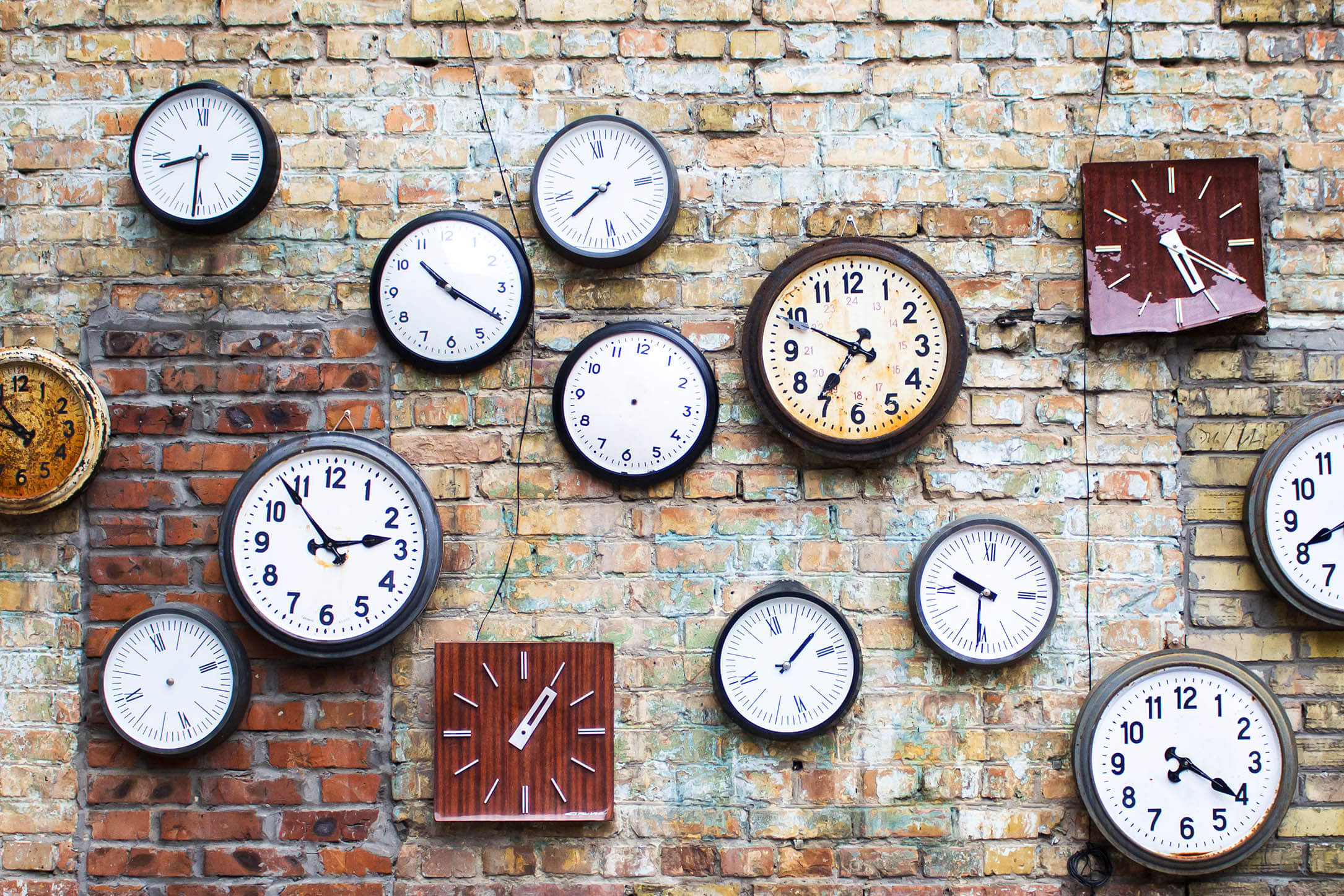 Lots of clocks on a brick wall