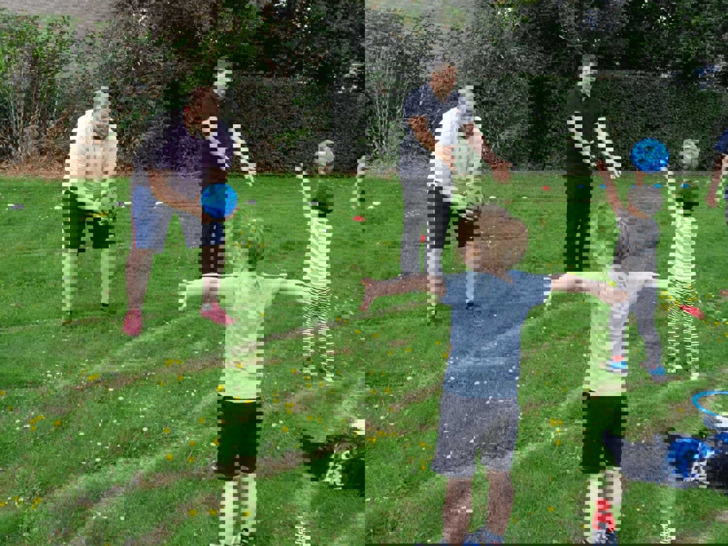 Two men playing catch with children 
