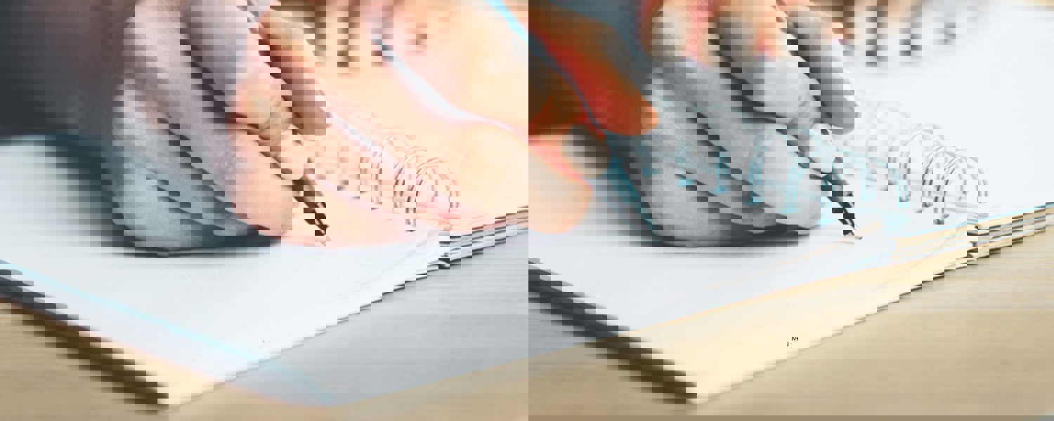 Close up of person writing in notebook