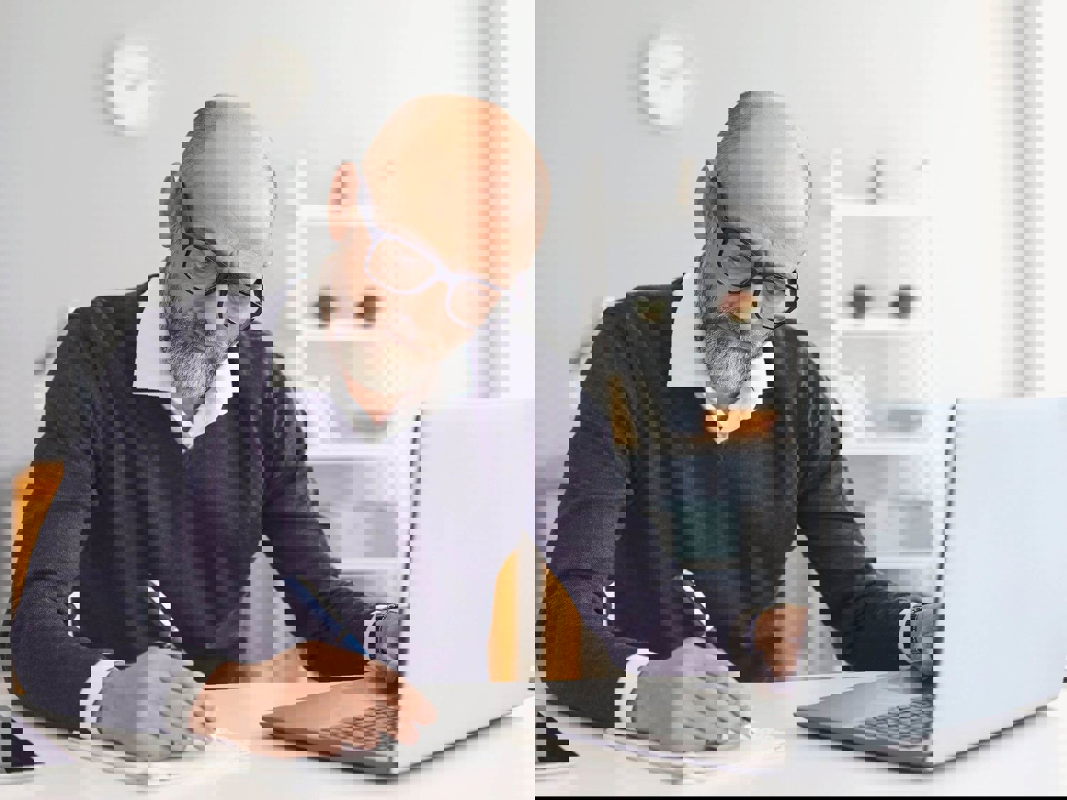 Man writing on notebook at laptop