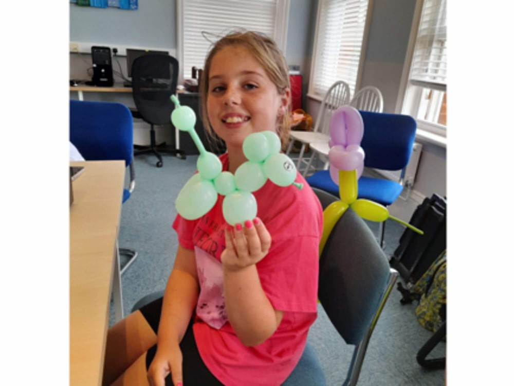 Girl smiling holding balloon animal