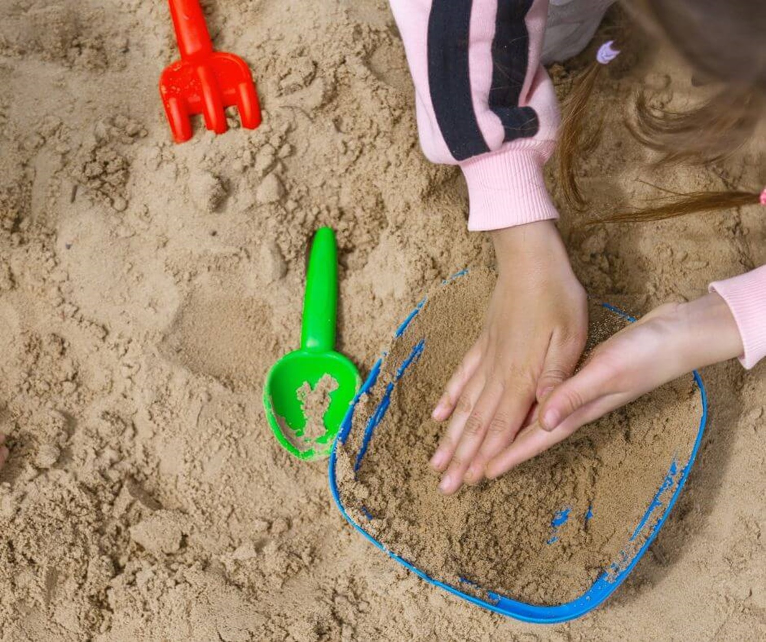 Young child's hands in sand