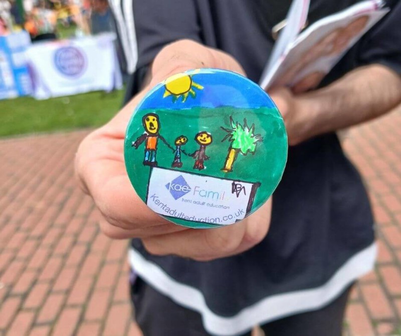 Person holding a badge made at a Family Learning event