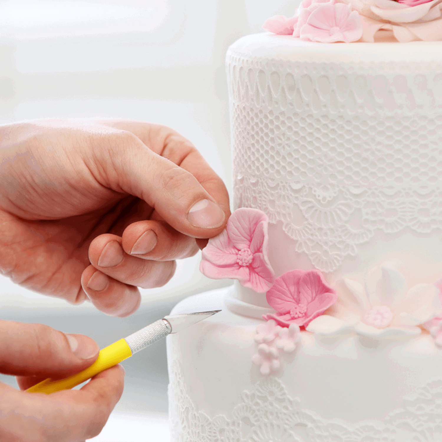 Person placing iced flowers on cake