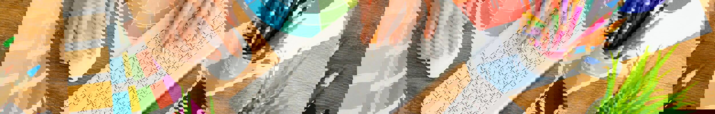 Person's hands typing on keyboard with camera and colour charts on desk