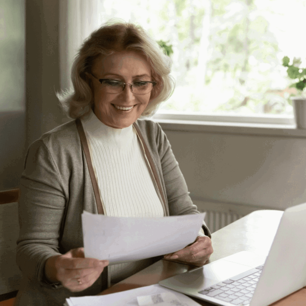 Lady at laptop holding paper