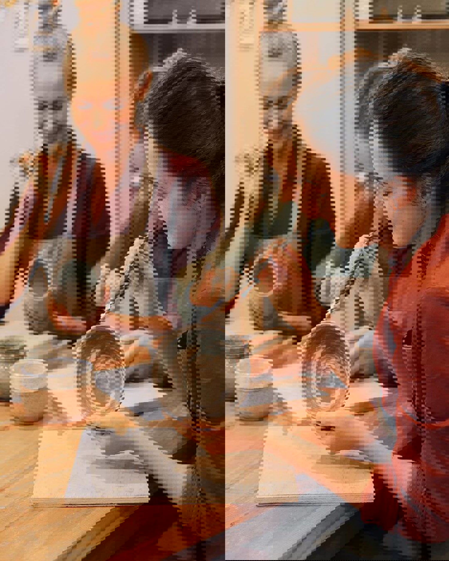 Three women decorating pottery pieces