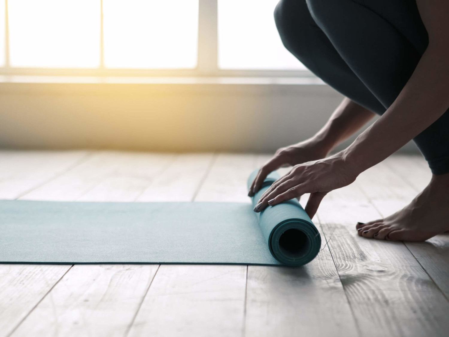 Person rolling out a yoga mat indoors