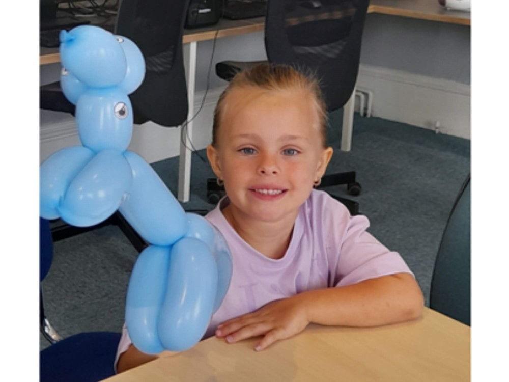 Girl smiling holding balloon animal