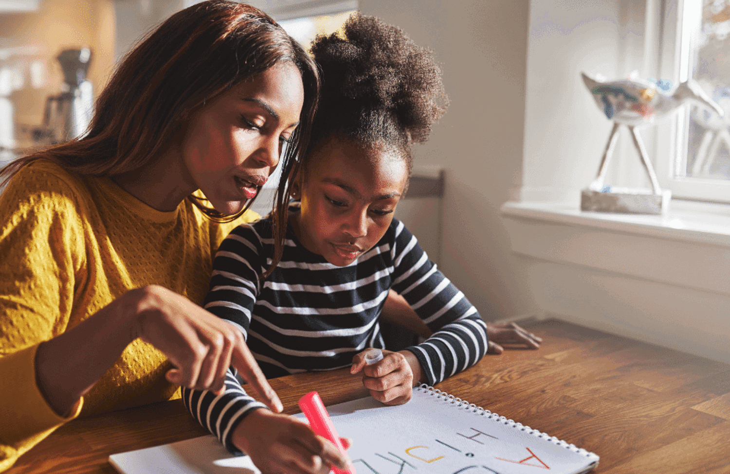 Woman showing girl how to write the alphabet