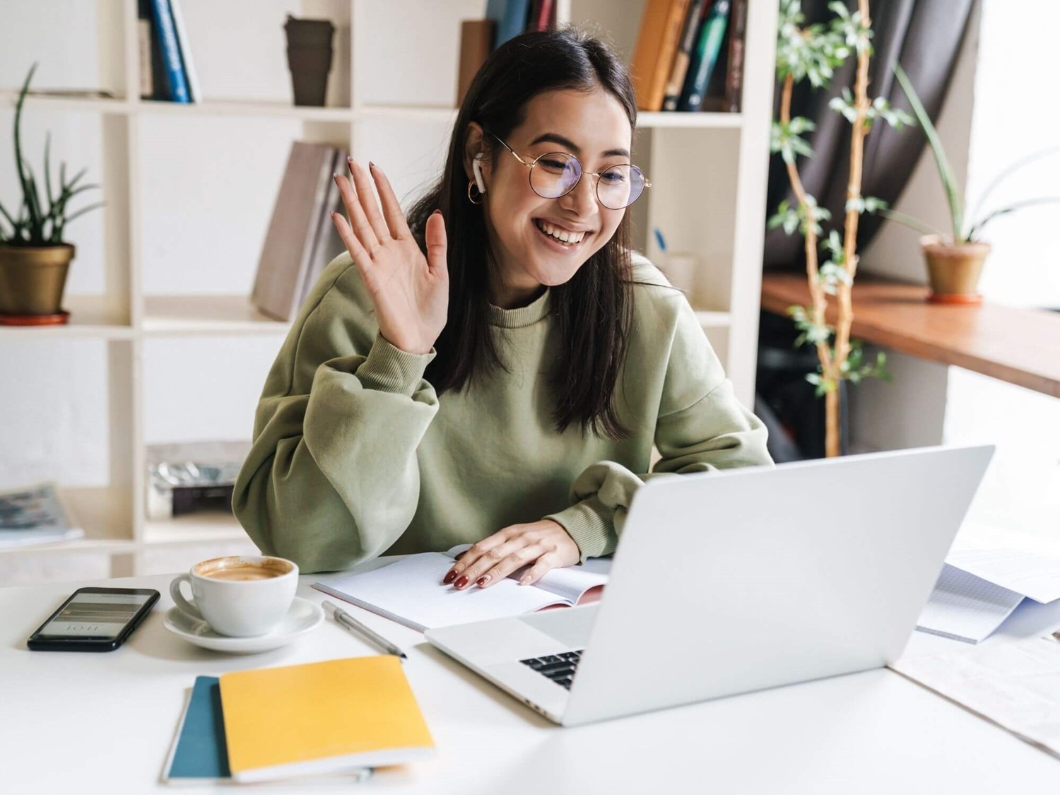 Woman smiling and waving at someone on laptop screen