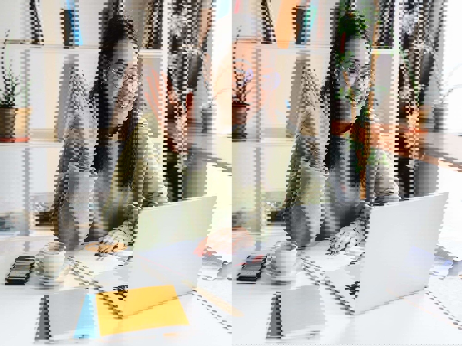 Woman smiling and waving at someone on laptop screen