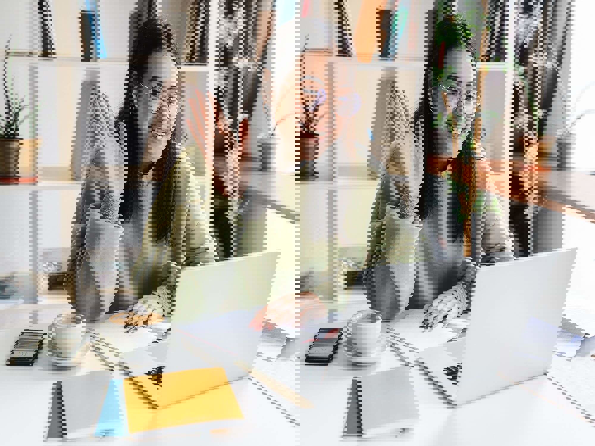 Woman smiling and waving at someone on laptop screen