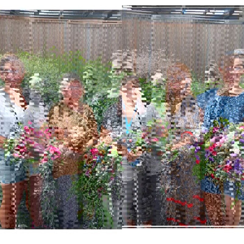 Learners and tutor holding bouquets of flowers 