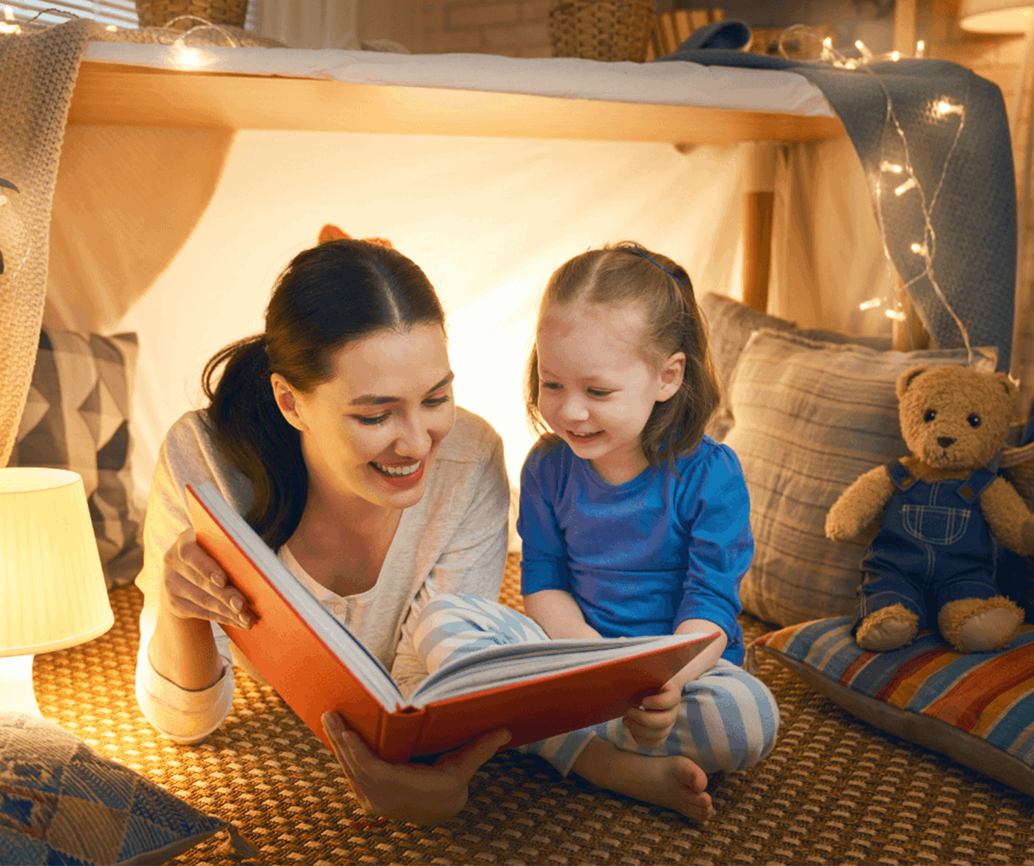 Mum reading to daughter under tent