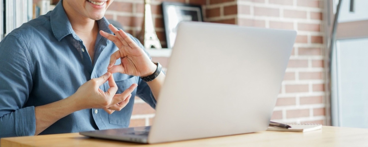 Person signing with hands while on laptop