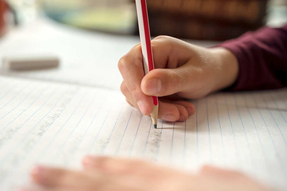 Writing on lined paper with a pencil