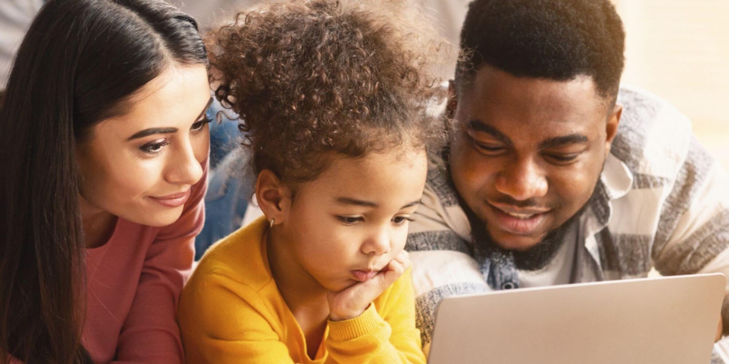 Parents looking at a laptop with their child