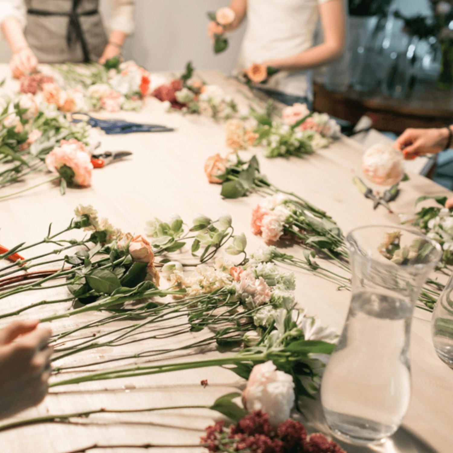 Group of people arranging flower stems on table