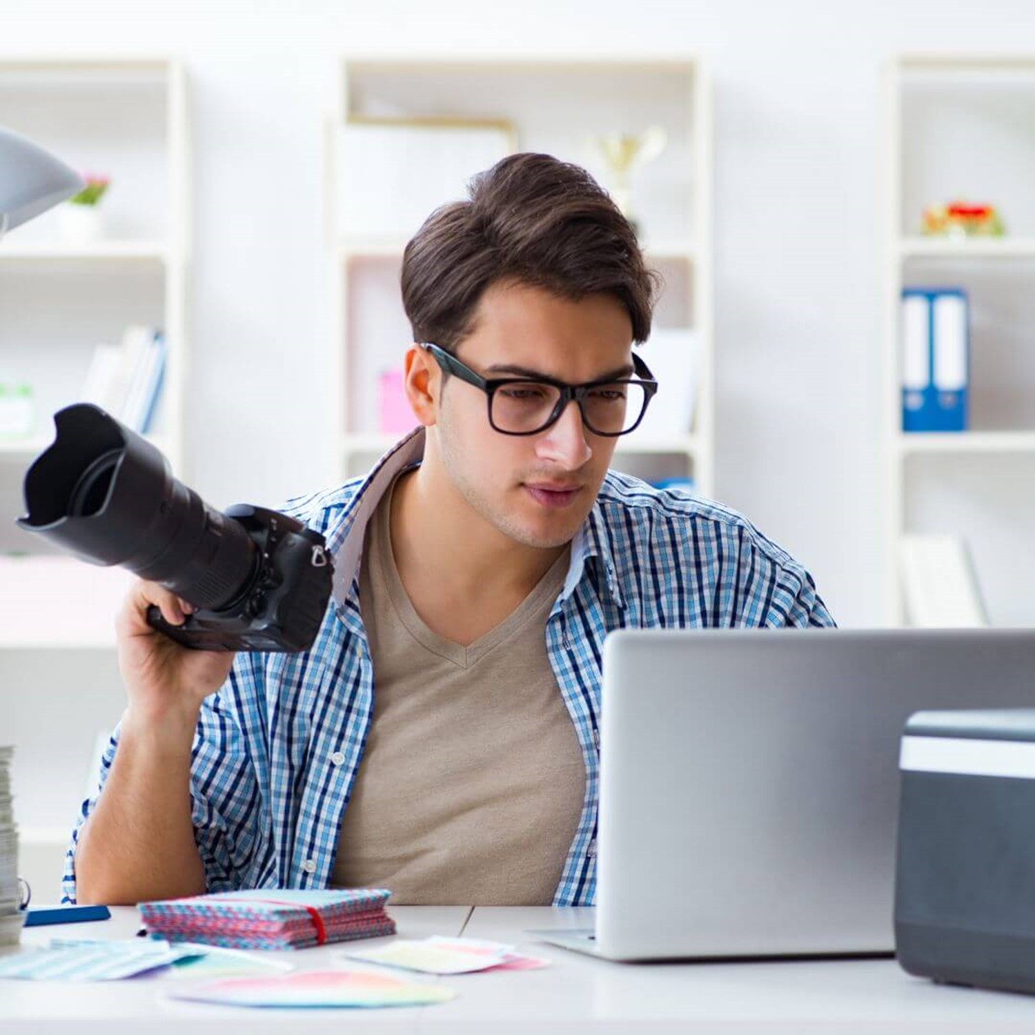 Man editing photos on a laptop while holding a camera