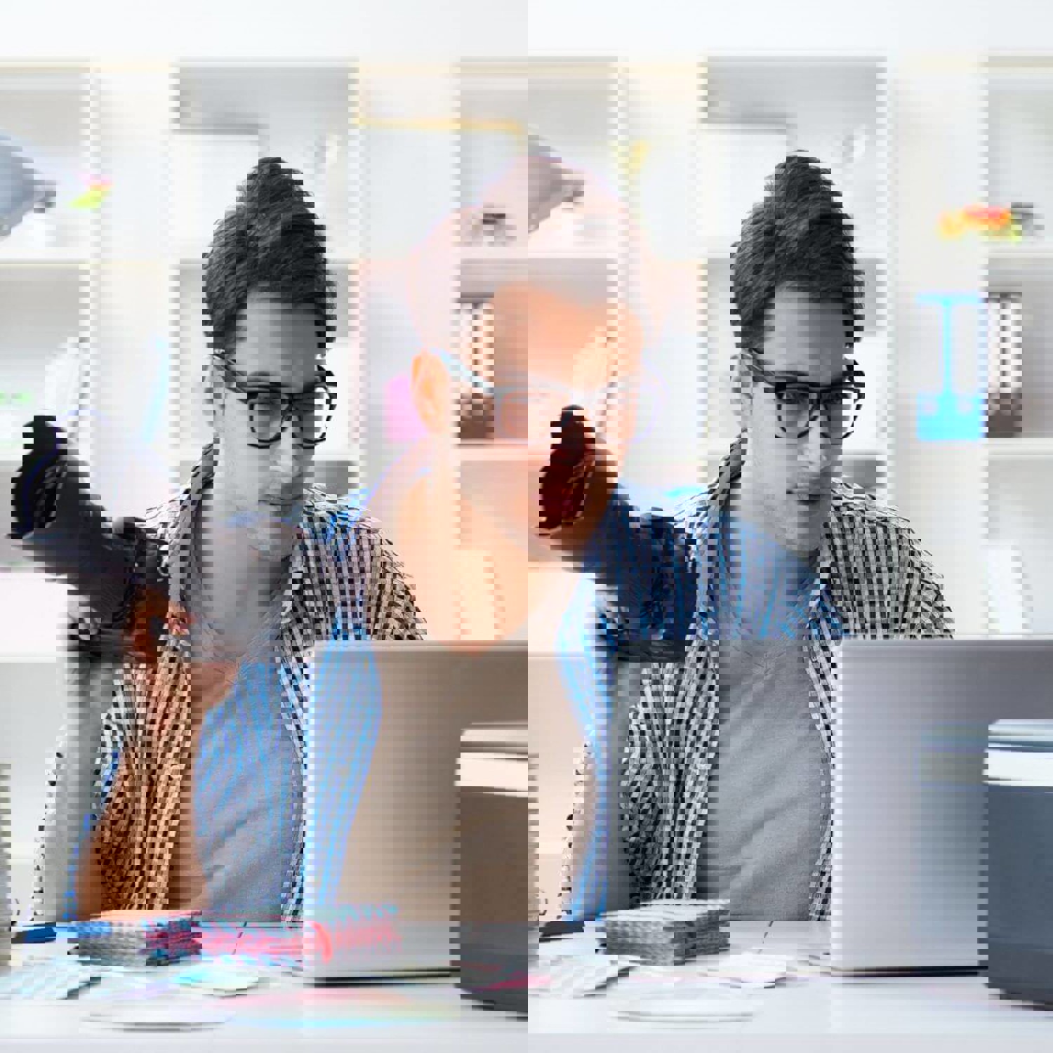 Man editing photos on a laptop while holding a camera