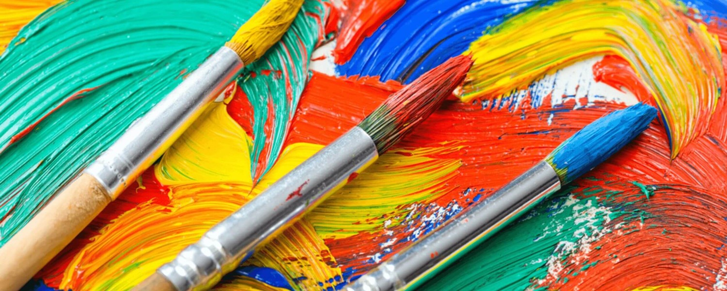 Paint brushes on top of bright paints