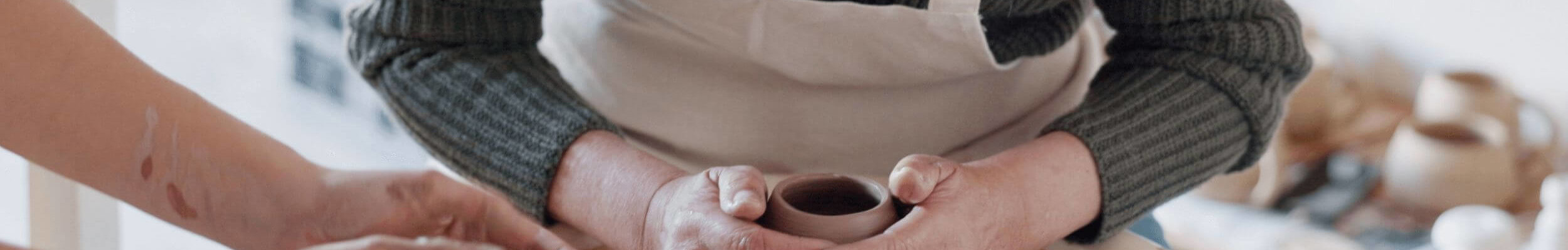 Close up of two people turning clay on pottery wheel 