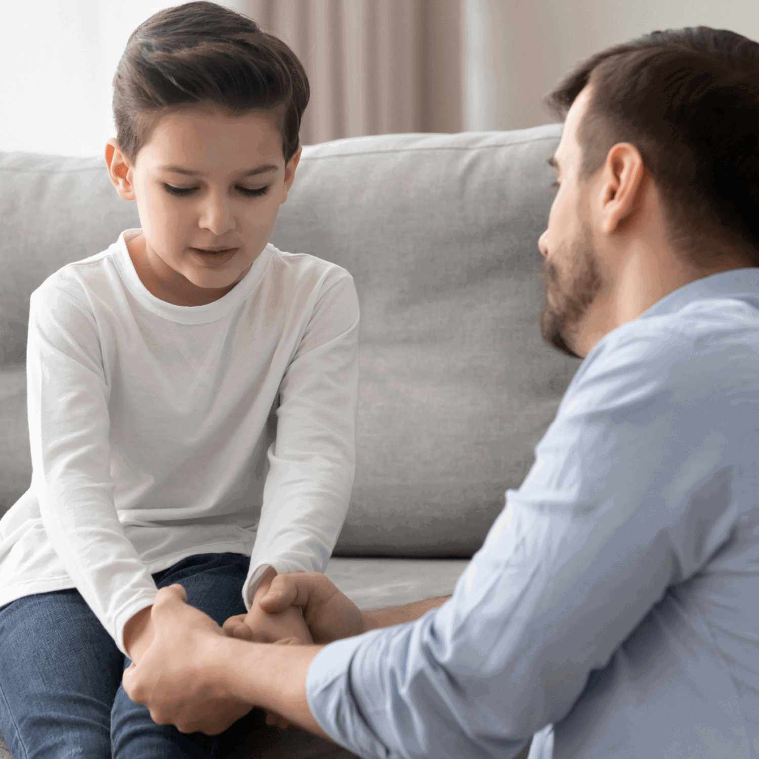 Boy with head down, holding hands with dad 