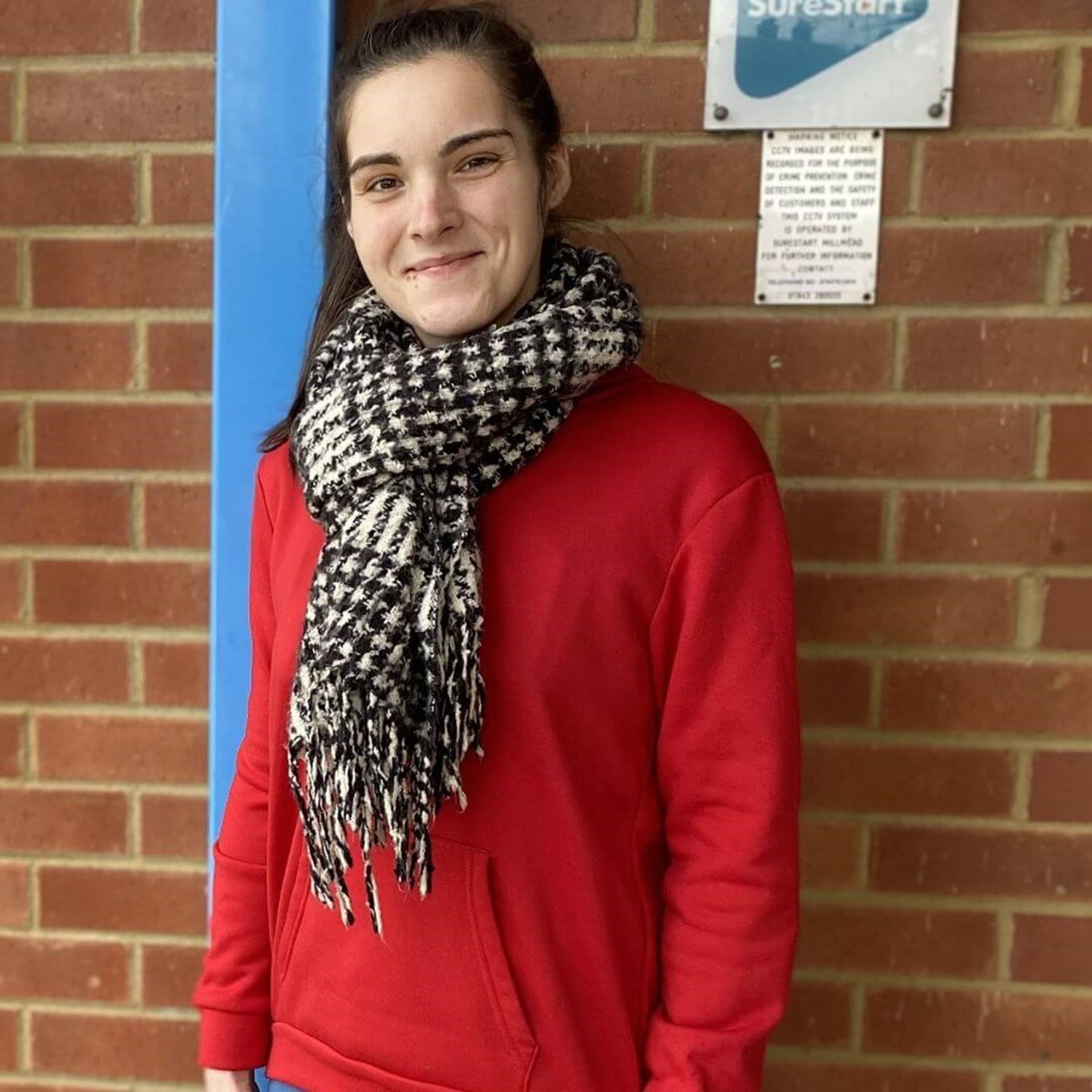 Girl smiling against brick wall