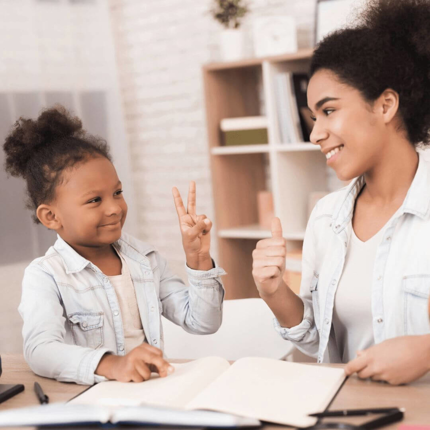 Girl doing peace sign to woman with thumbs up