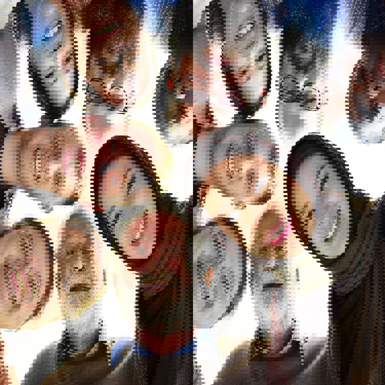 Group of people standing in a circle, looking down at the camera smiling