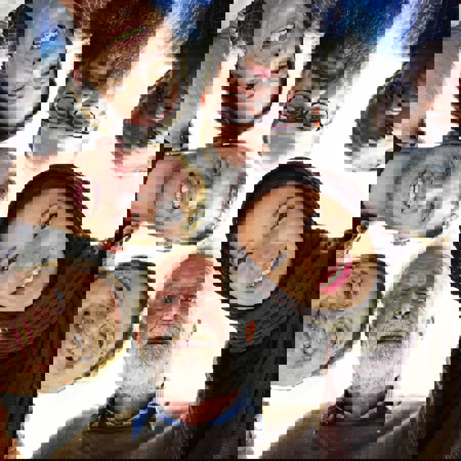 Group of people standing in a circle, looking down at the camera smiling