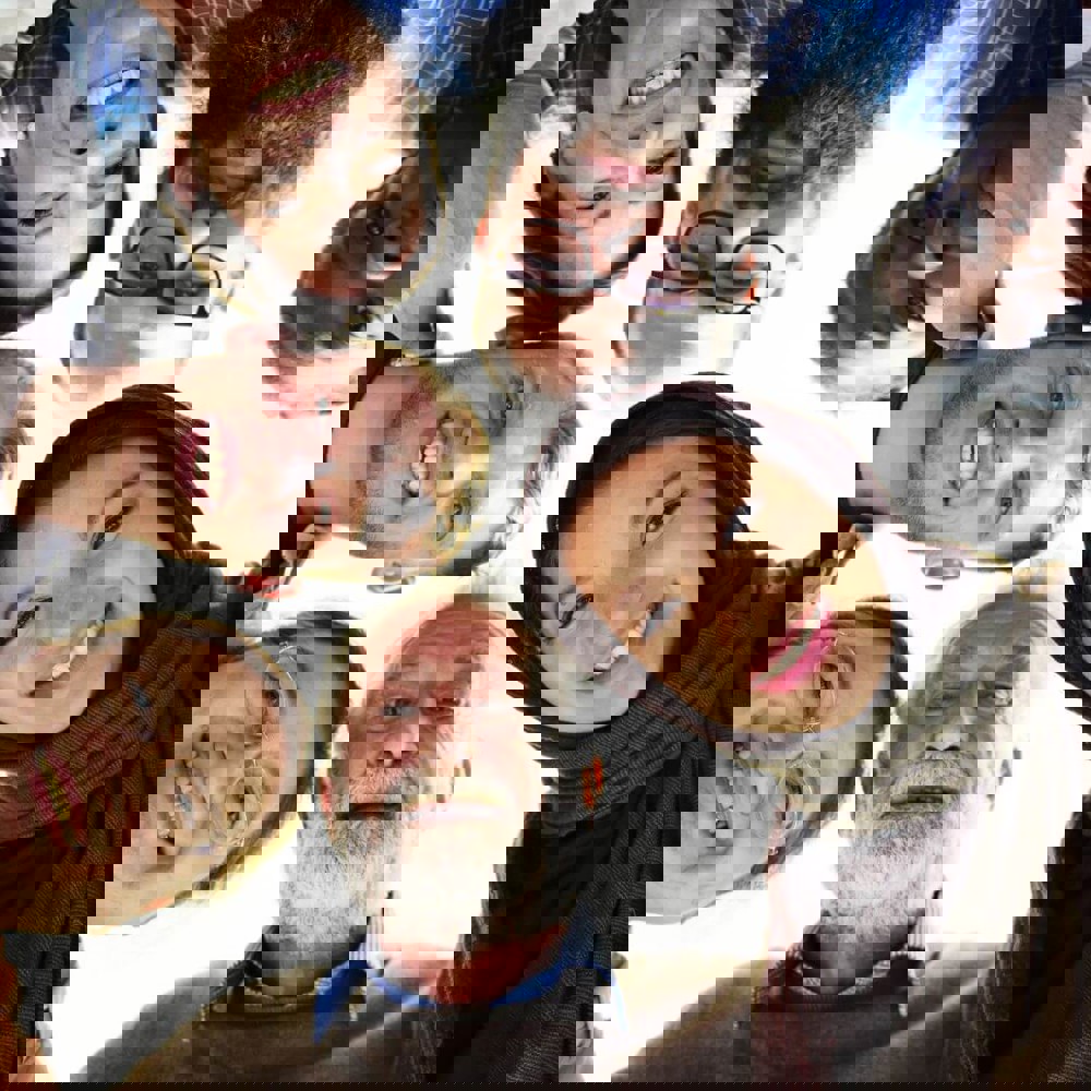 Group of people standing in a circle, looking down at the camera smiling