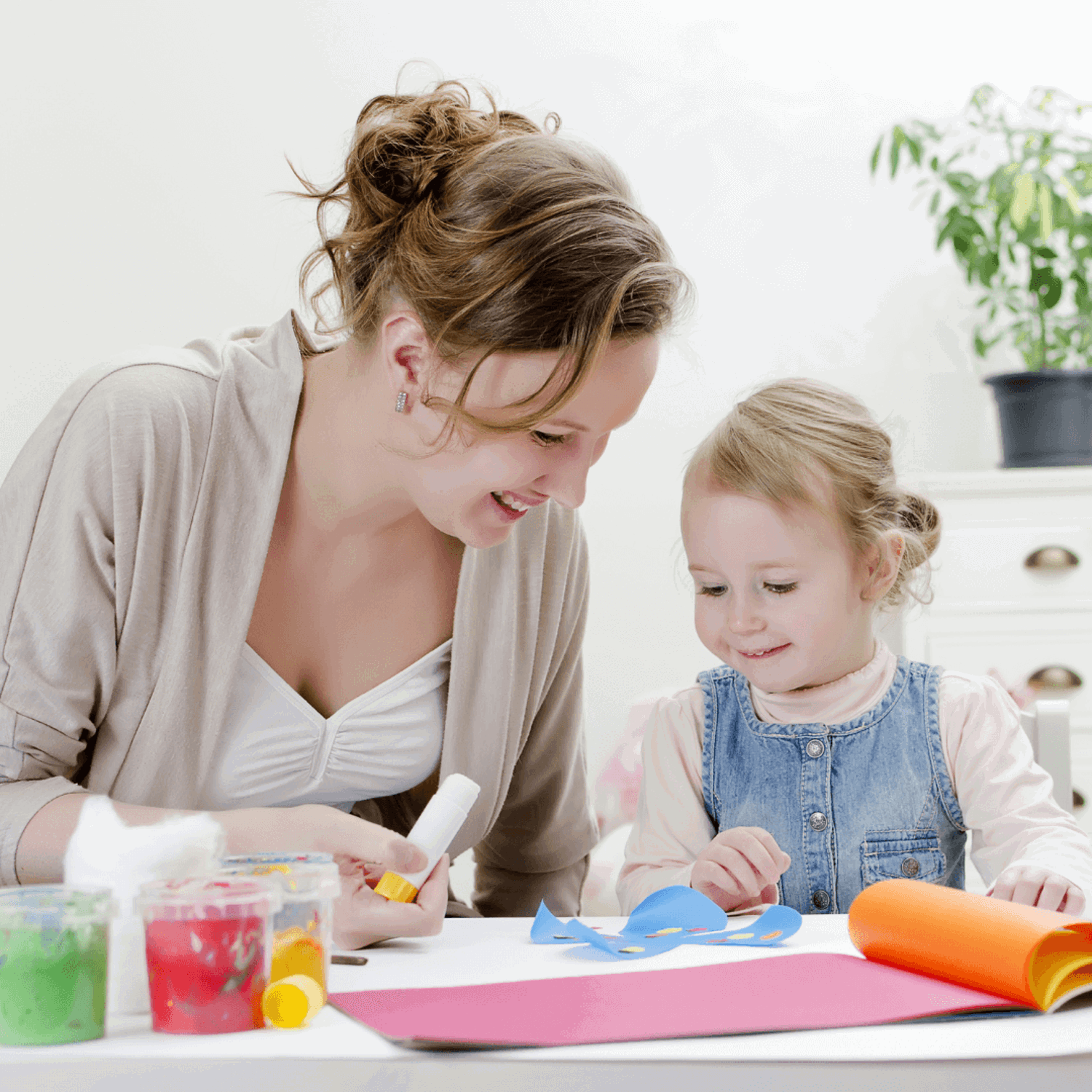 Woman holding glue stick with child doing crafts